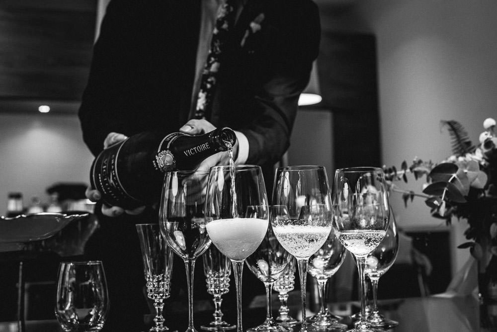 groom pouring wine in glasses