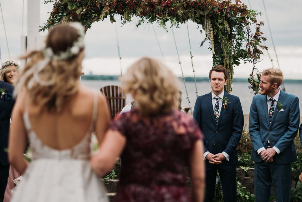 groom looking at bride coming down the aisle