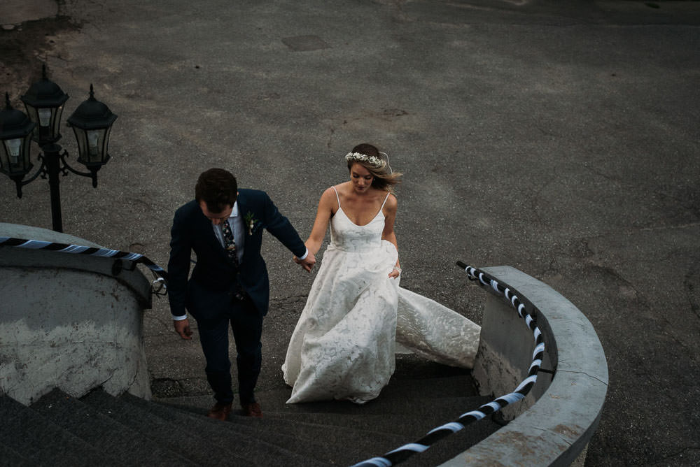 groom leading bride up stairs by hand
