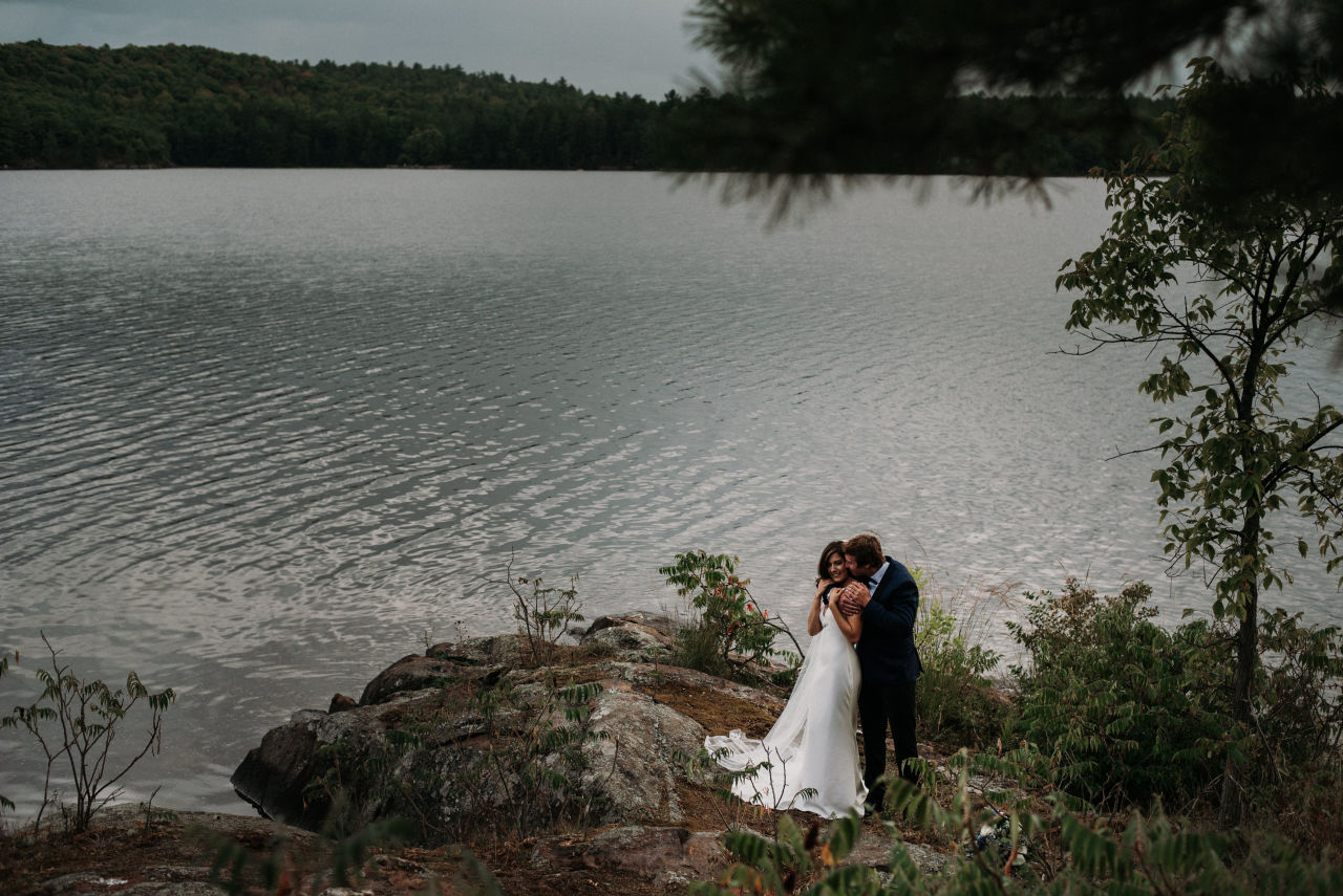 couple embrace on the shore of lake