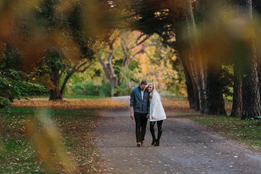 couple walking down path while cuddling