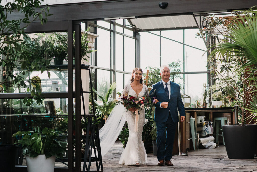 father walking bride down aisle during wedding at aquatopia