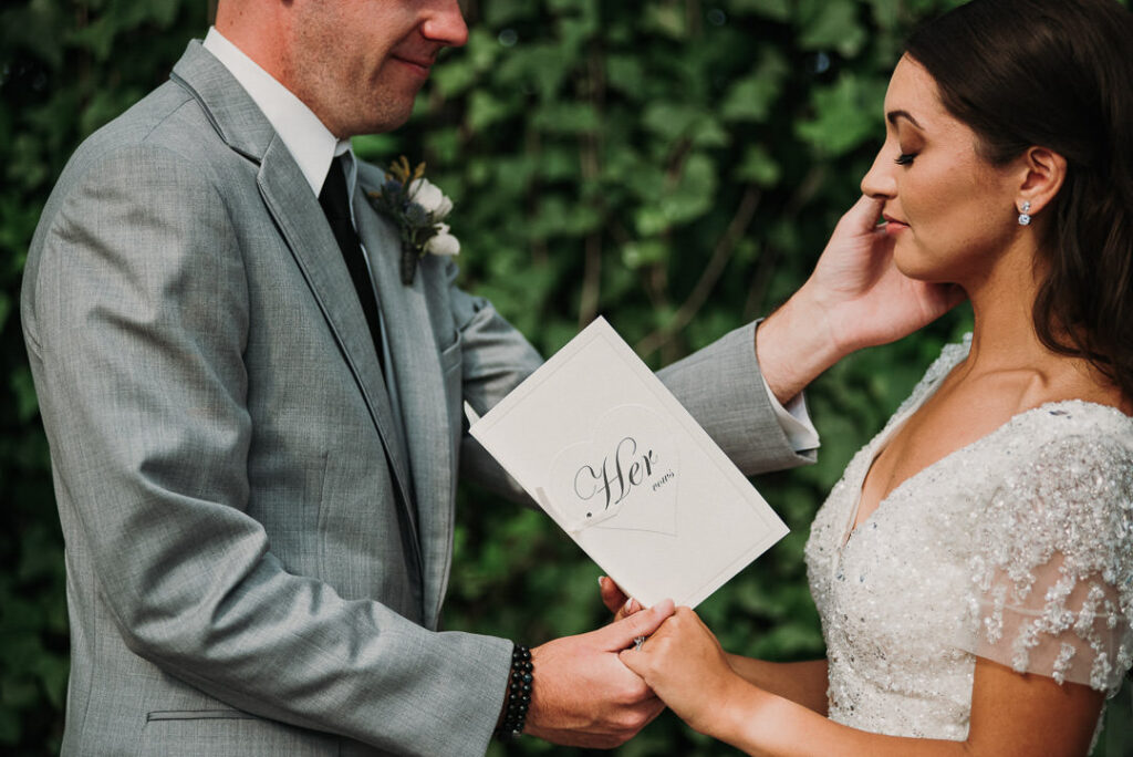 groom wiping tears off of bride's cheek during their wedding at aquatopia