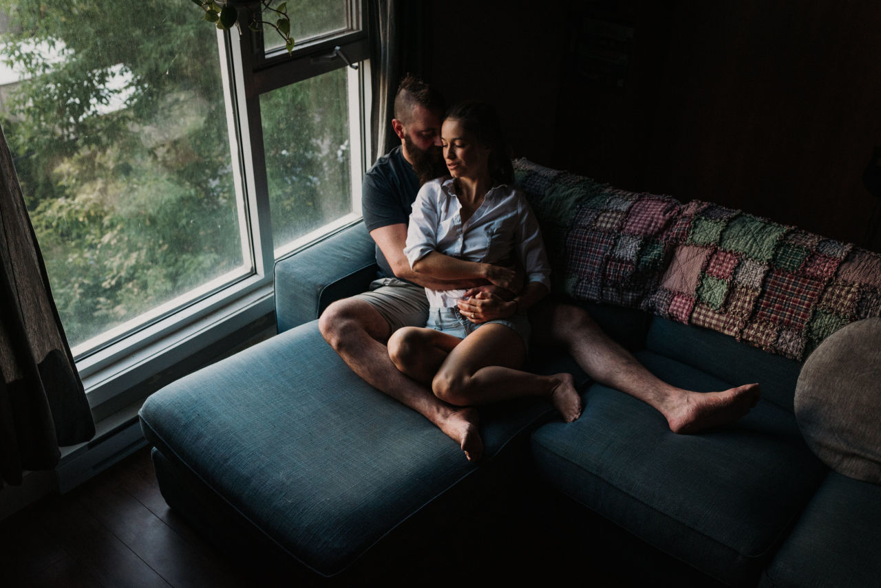 home engagement session photo of couple snuggling on couch