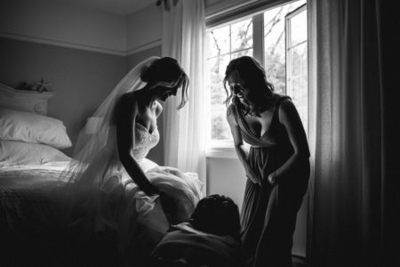bridesmaid helping bride put shoes on