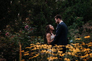 bride and groom standing in flowers in embrace