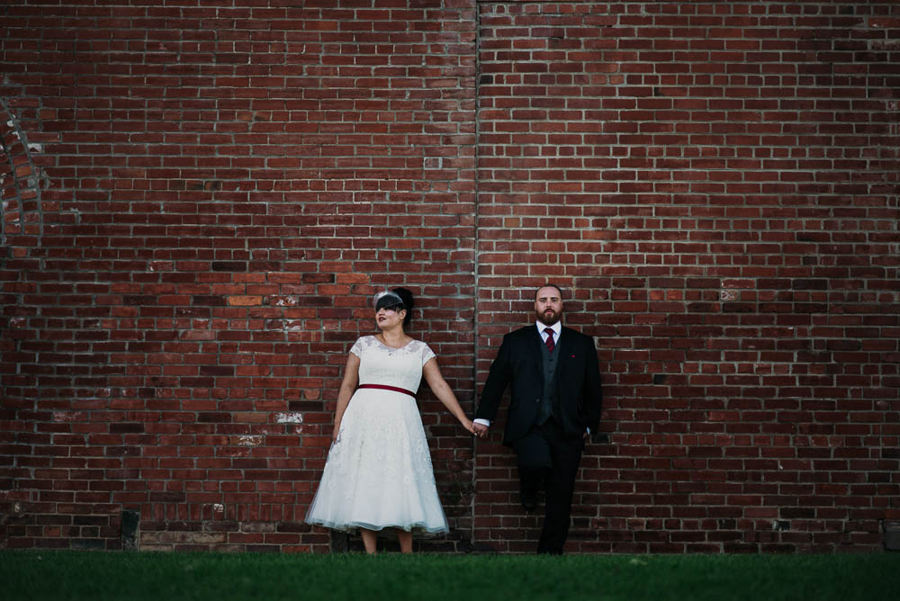 bride and groom leaning against wall