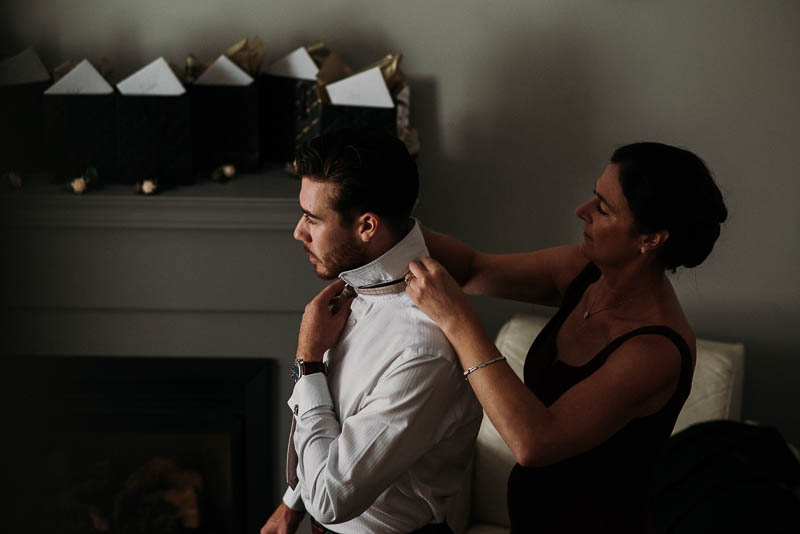 mother of groom buttoning his shirt