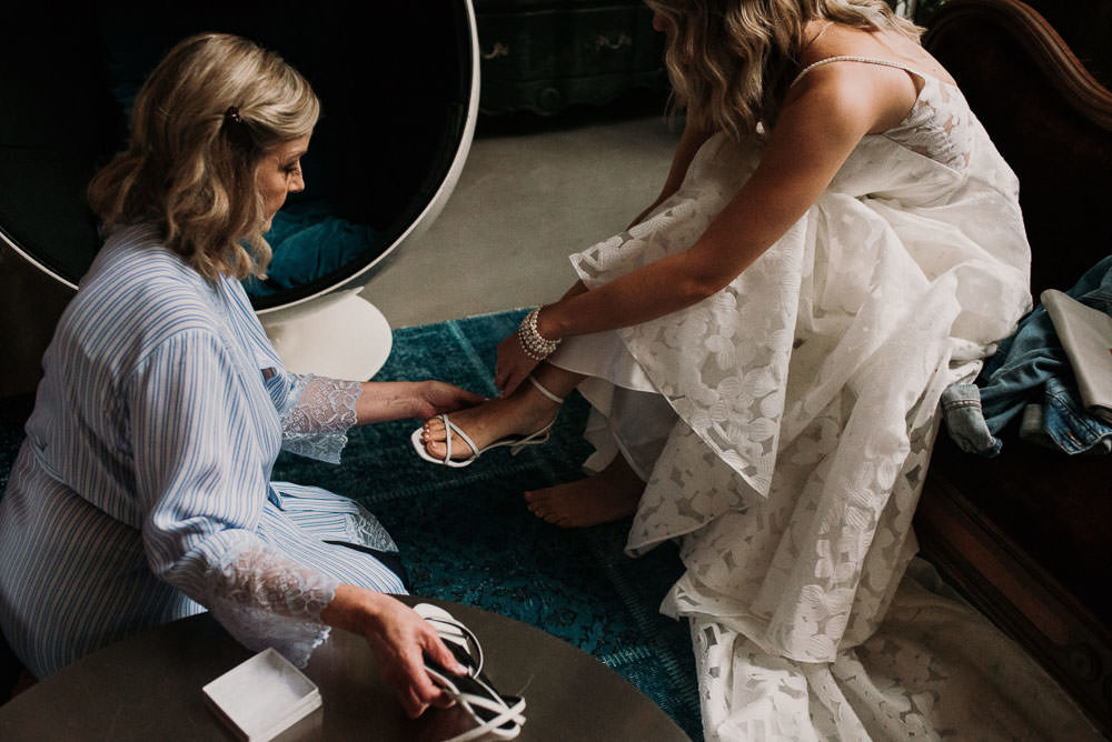 mother helping bride put shoes on