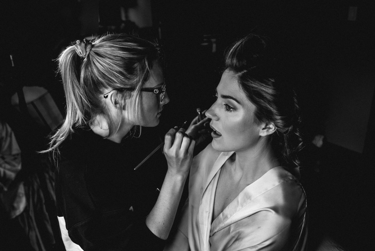 make up artist applying lashes on bride as she gets ready for her wedding
