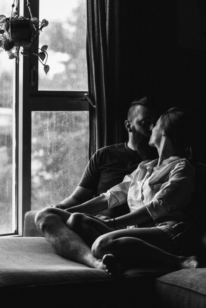 couple kissing on couch during home engagement session