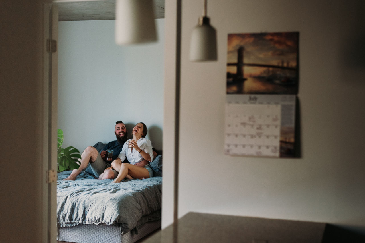 couple laughing in bed during their home engagement session