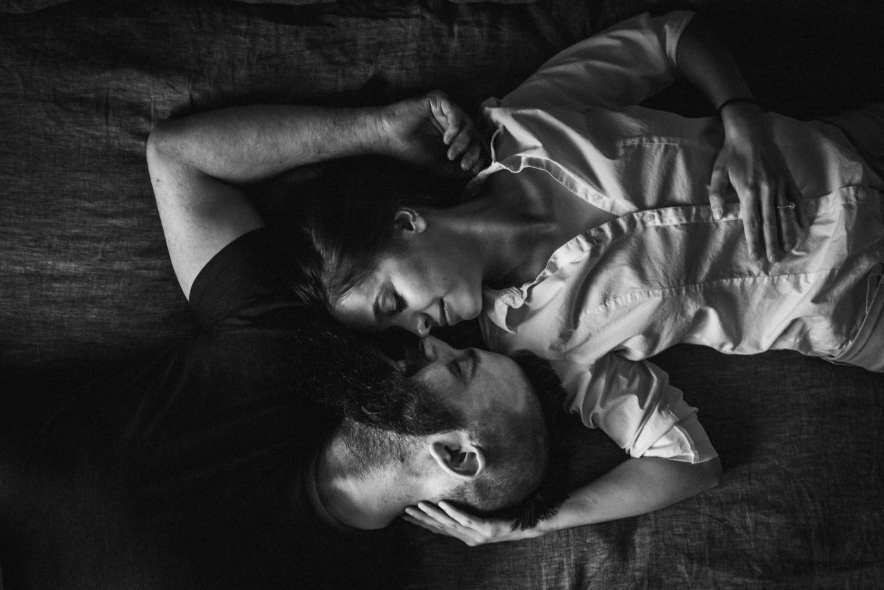 home engagement session photo of couple laying face to face on bed